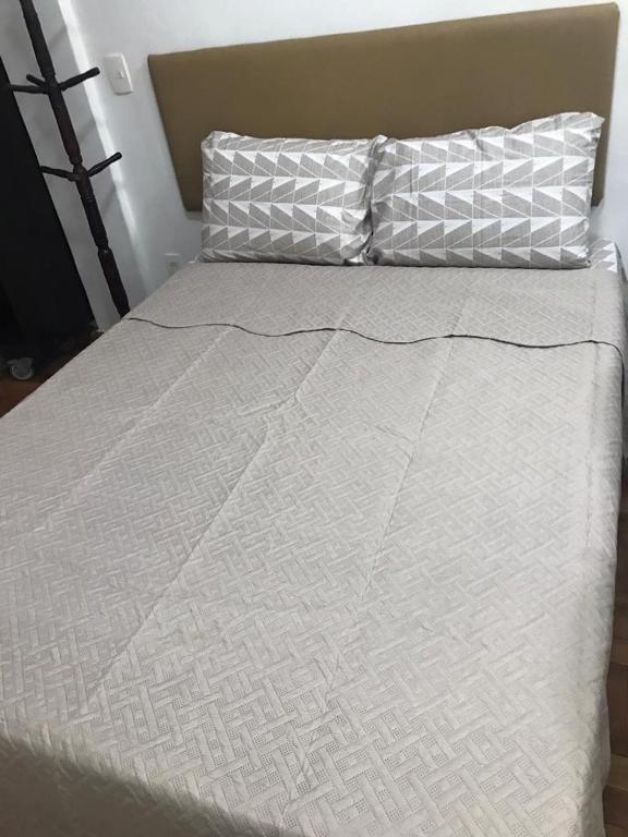 a bed with a white comforter and a pillow at STUDIO IPANEMA CONFORTÁVEL in Rio de Janeiro