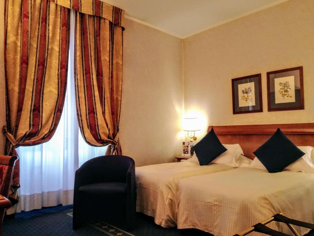 a hotel room with two beds and a chair and a window at Hotel Cappello D'Oro, BW Signature Collection in Bergamo