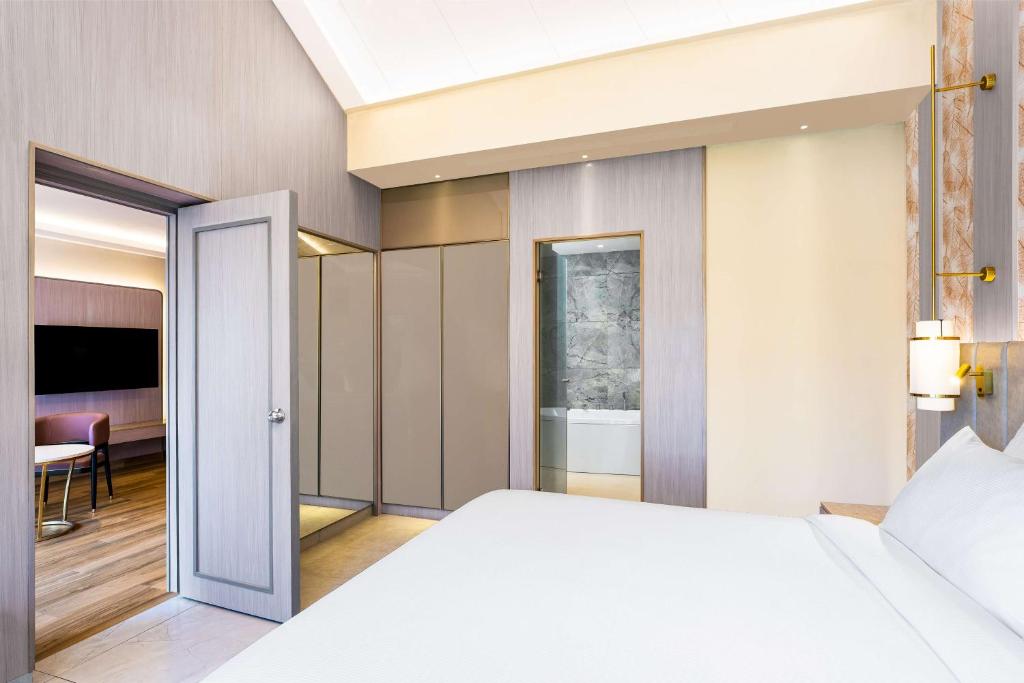 a bedroom with a white bed and a dining room at DoubleTree by Hilton Hotel Goa - Arpora - Baga in Baga