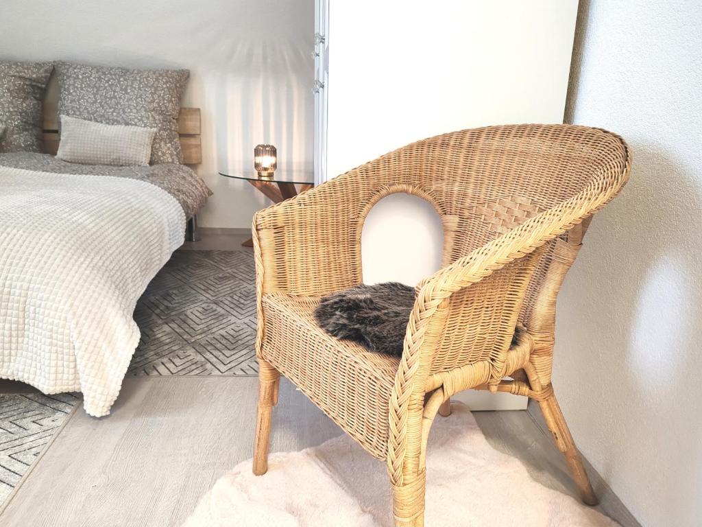 a cat sitting in a wicker chair next to a bed at Top Wohnung in Mainz-Kostheim in Mainz-Kostheim