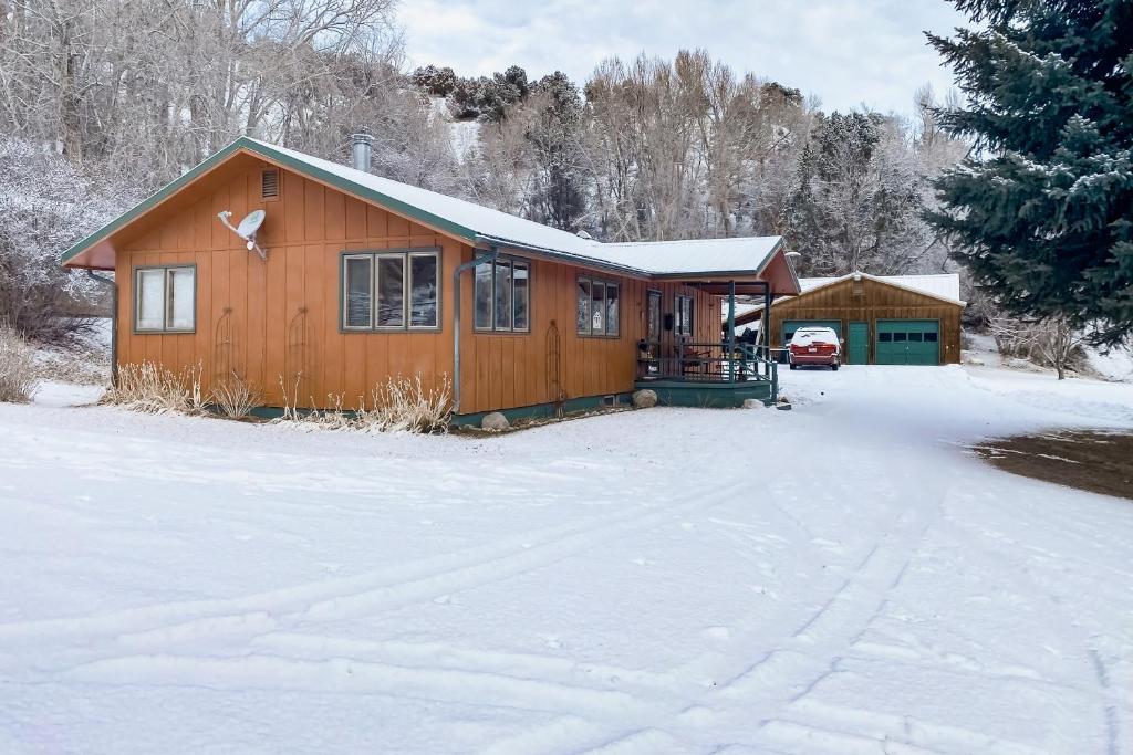 a cabin in the snow with a snow covered driveway at Riverfront Paradise - Entire Home in Gypsum