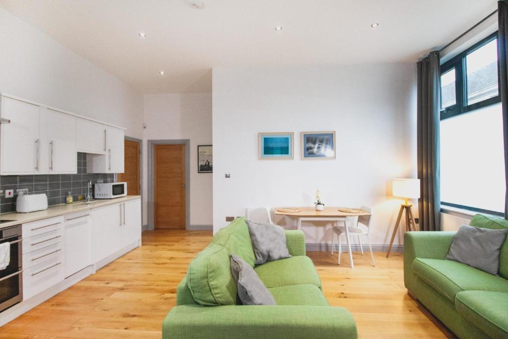 a living room with a green couch and a kitchen at Stylish modern 1 bedroom property in Greenwich! in London