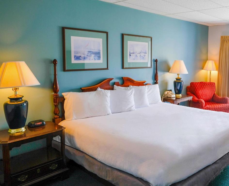 1 dormitorio con 1 cama blanca grande y 1 silla roja en Boothbay Harbor Inn, en Boothbay Harbor