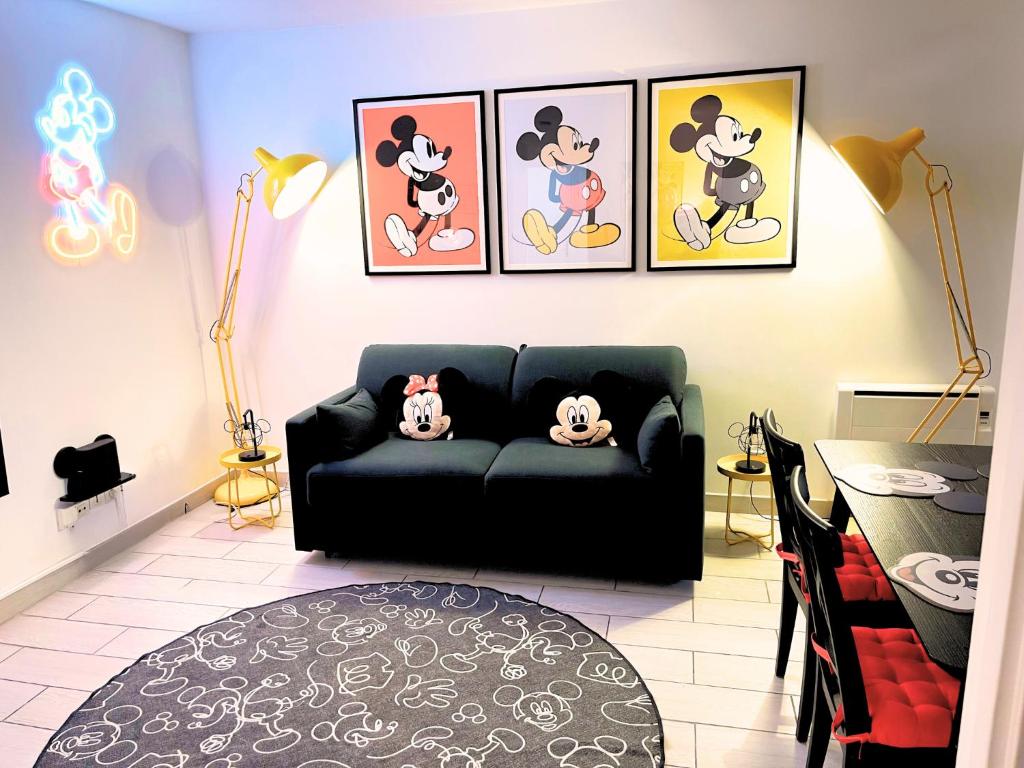 un salon avec un canapé noir et des tableaux au mur dans l'établissement Appartement de Mickey à 5 min de Disneyland Paris, à Serris