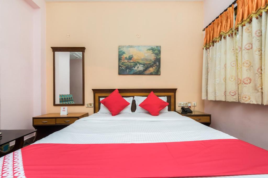 a bedroom with a large bed with red pillows at Super Capital O Hotel Bidisha in Digha