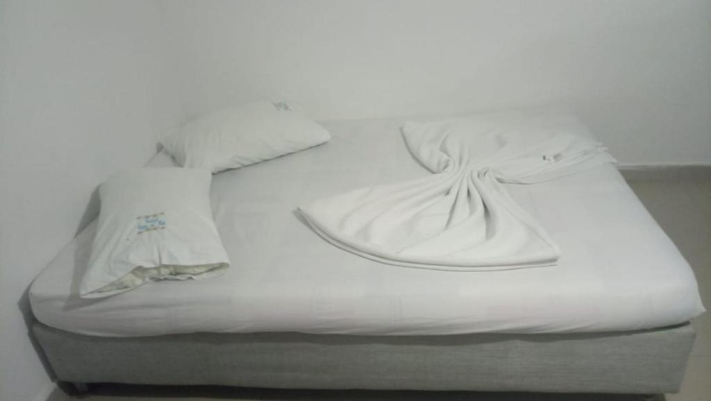 a white bed with two white shirts on it at HOTEL VISTA AL MAR habitacion para 2 personas in Rodadero