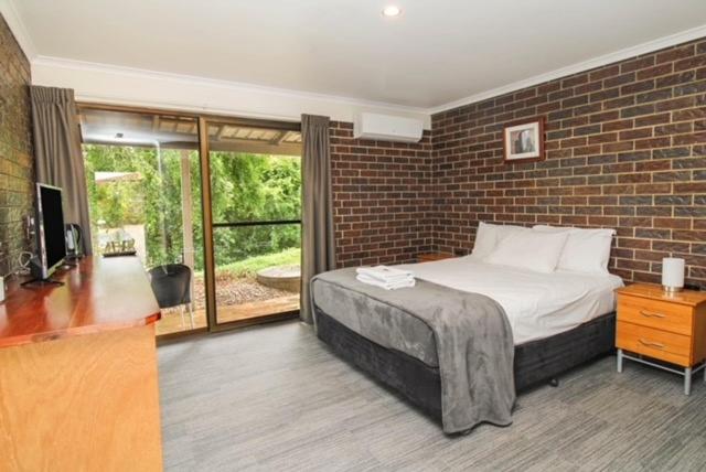 a bedroom with a bed and a brick wall at Tranquil Park in Maleny