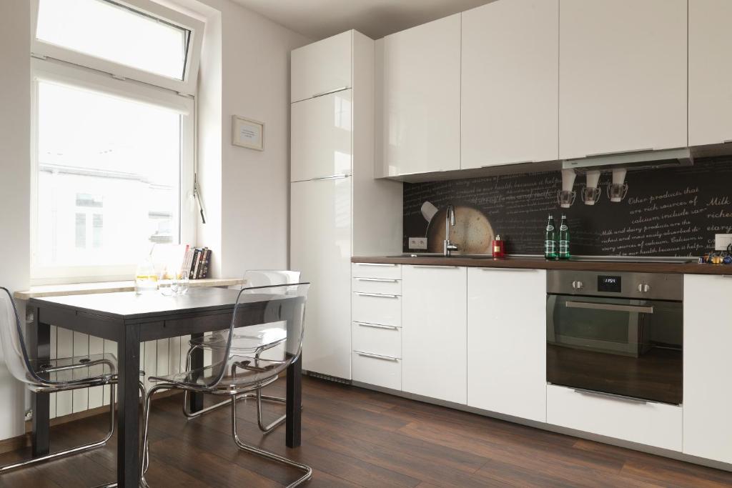 een keuken met witte kasten en een tafel met stoelen bij Apartament Chmielna by Your Freedom in Warschau