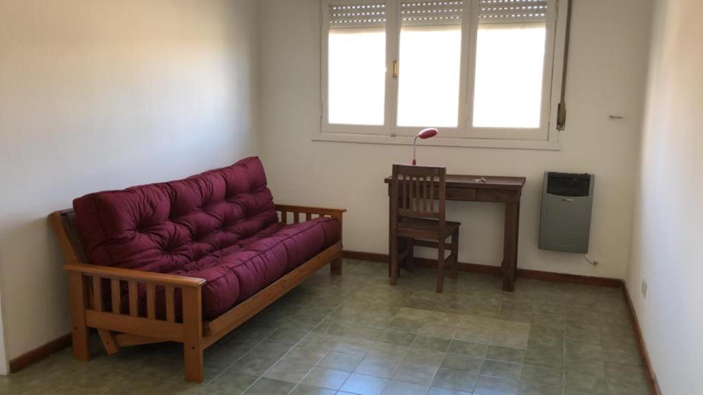 een woonkamer met een paarse bank en een bureau bij Cómodo Departamento Hogareño in Bariloche