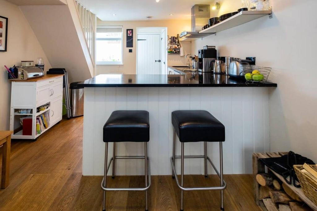 a kitchen with two bar stools at a counter at Super central cosy & cute North Laine cottage in Brighton & Hove