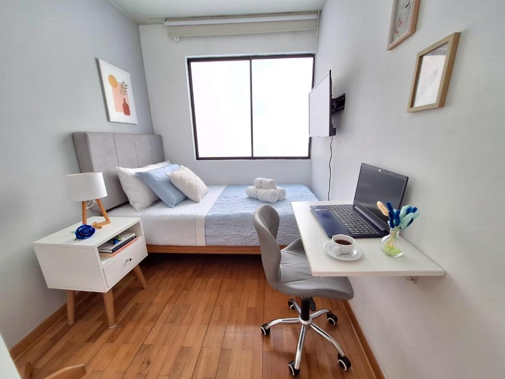 a bedroom with a bed and a desk with a laptop at Habitación baño Compartido La Paz 2 in Lima