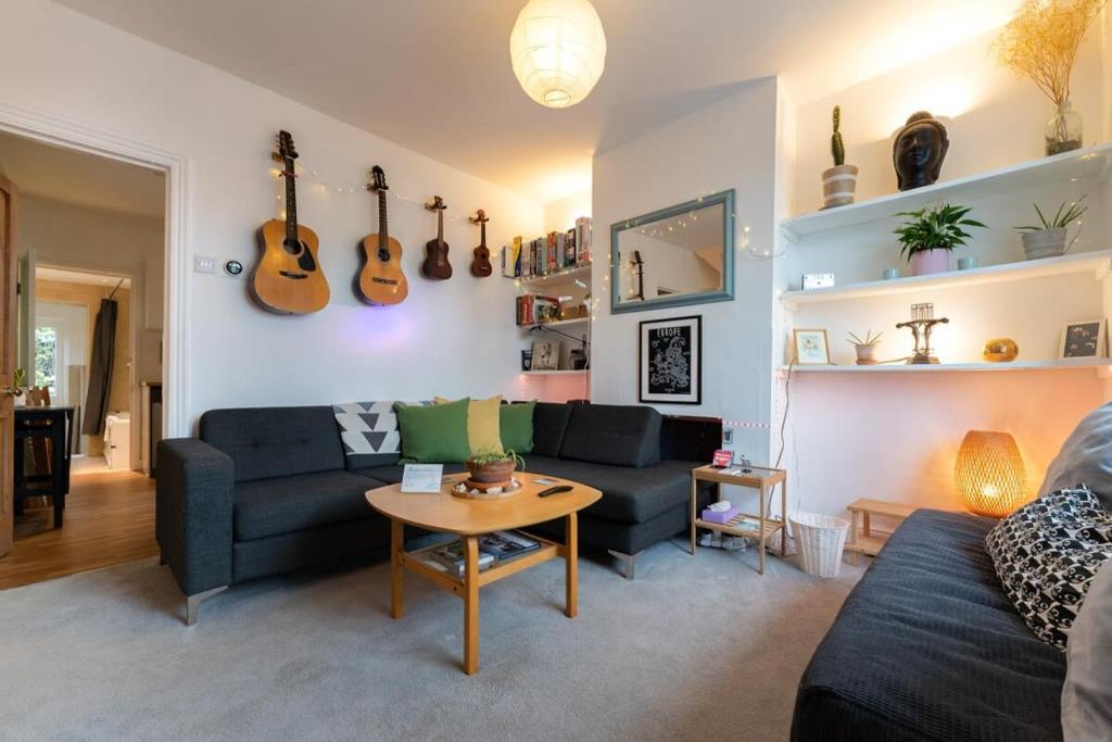a living room with a couch and guitars on the wall at Charming 2 bed Flat with Secluded Garden in Brighton & Hove