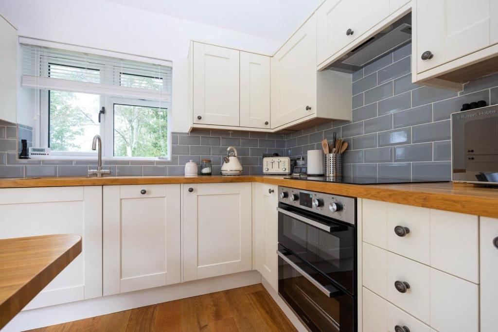 a kitchen with white cabinets and a sink and a stove at Countryside Cottage with Stunning Views in Fletching