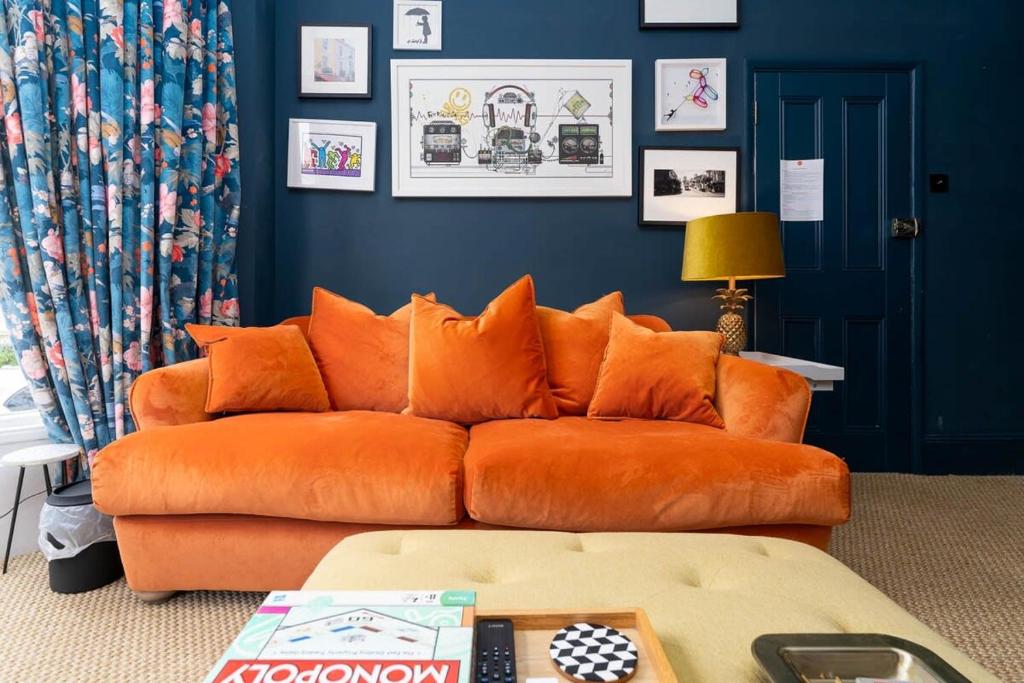 - un canapé orange dans un salon aux murs bleus dans l'établissement Contemporary & Colourful Flat + Garden, à Brighton et Hove
