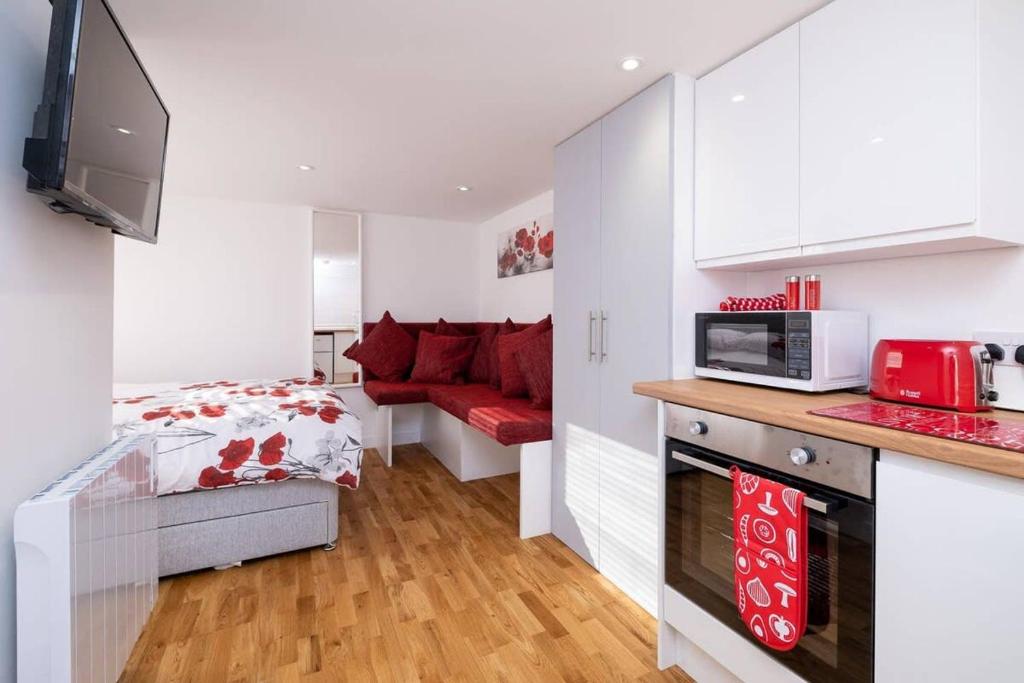 a small bedroom with a bed and a red couch at Brand new studio apartment with parking in Brighton & Hove