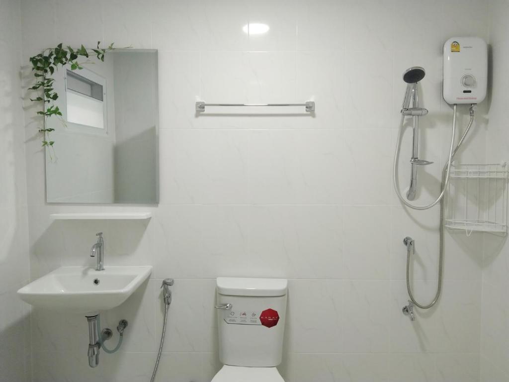 La salle de bains blanche est pourvue de toilettes et d'un lavabo. dans l'établissement AMA residences, à Bangkok