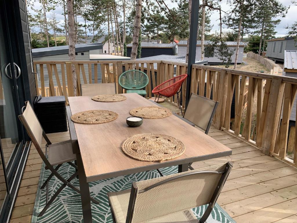 une table et des chaises en bois sur une terrasse dans l'établissement Chalet de standing pour 4 pers., piscine couverte et chauffée, à deux pas de la plage, Wi-Fi gratuit - FR-1-361-515, à Jullouville