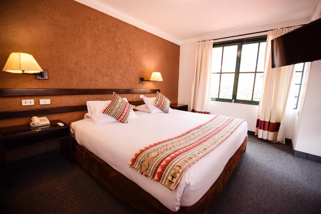 庫斯科的住宿－Hotel Raymi，一间设有大床和窗户的酒店客房