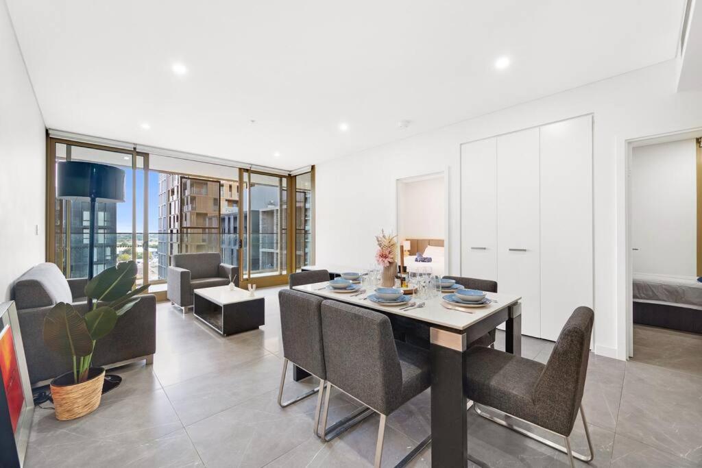 a dining room and living room with a table and chairs at Sydney Olympic Park Modern 3 Bedroom with Pool & Free Parking in Sydney