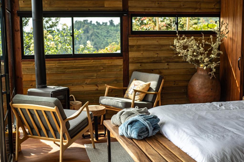 a bedroom with a bed and two chairs and a table at Owl's Watch Nature Retreat in Manizales