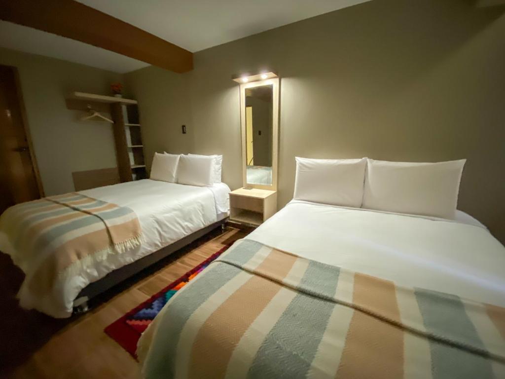 1 dormitorio con 2 camas y espejo en Huallata Hotel Boutique, en Huaraz