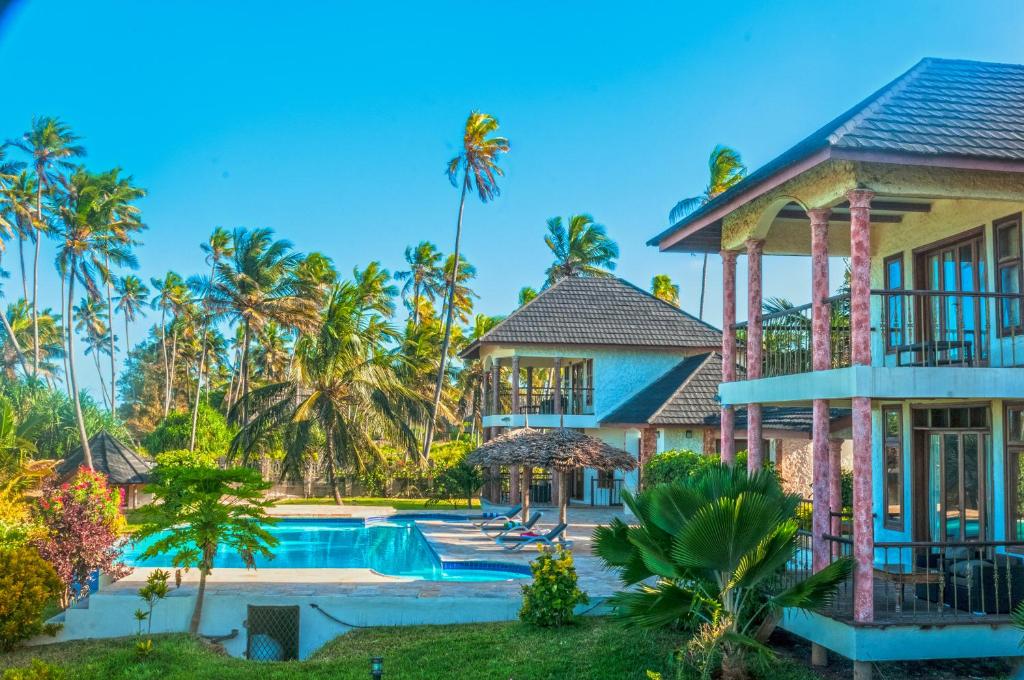 a villa with a swimming pool and palm trees at Zawadi Beach Villas in Matemwe