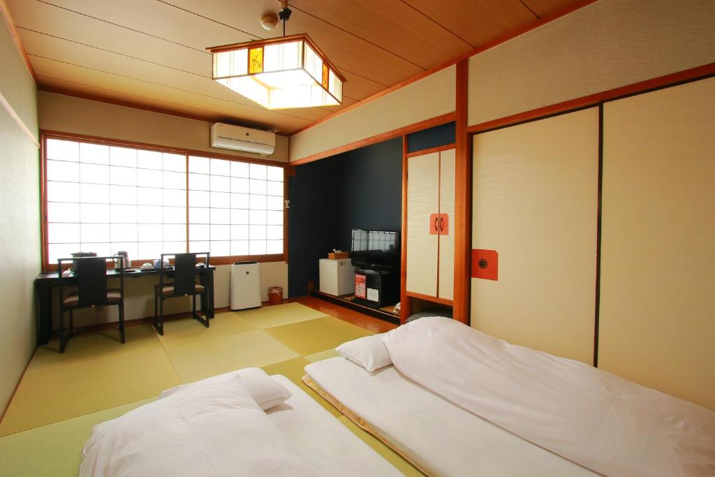 une chambre avec un lit et un bureau dans l'établissement 旅館　松乃湯, à Kutami