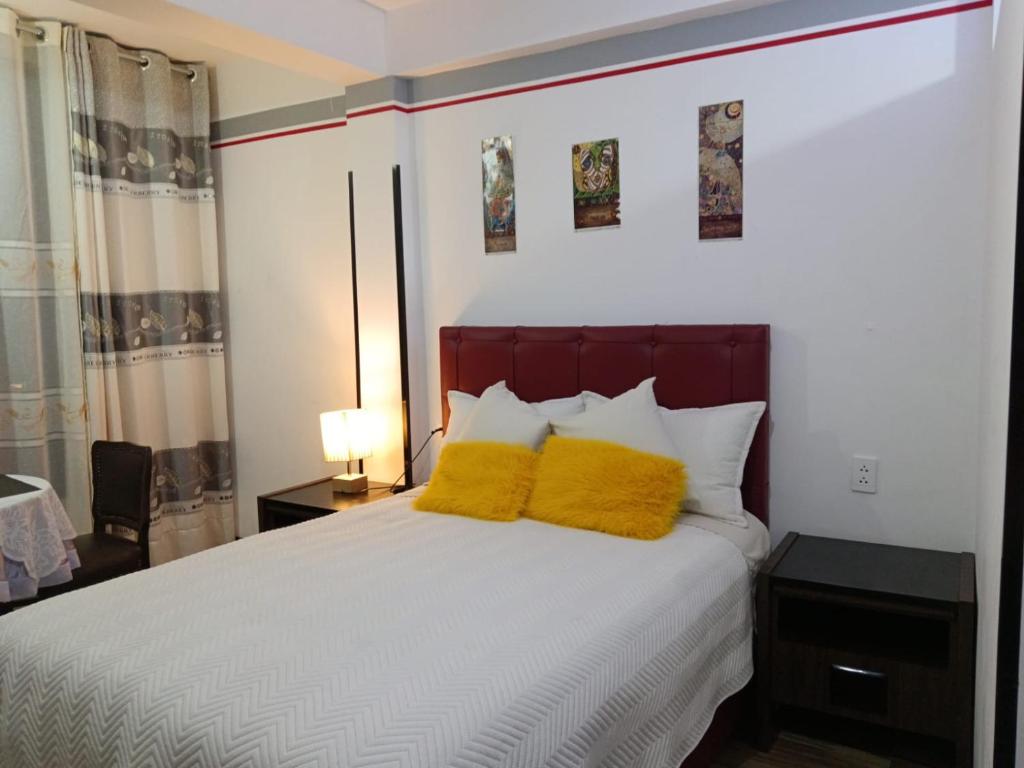 a bedroom with a bed with two yellow pillows at Casa Qura Qura in Cochabamba