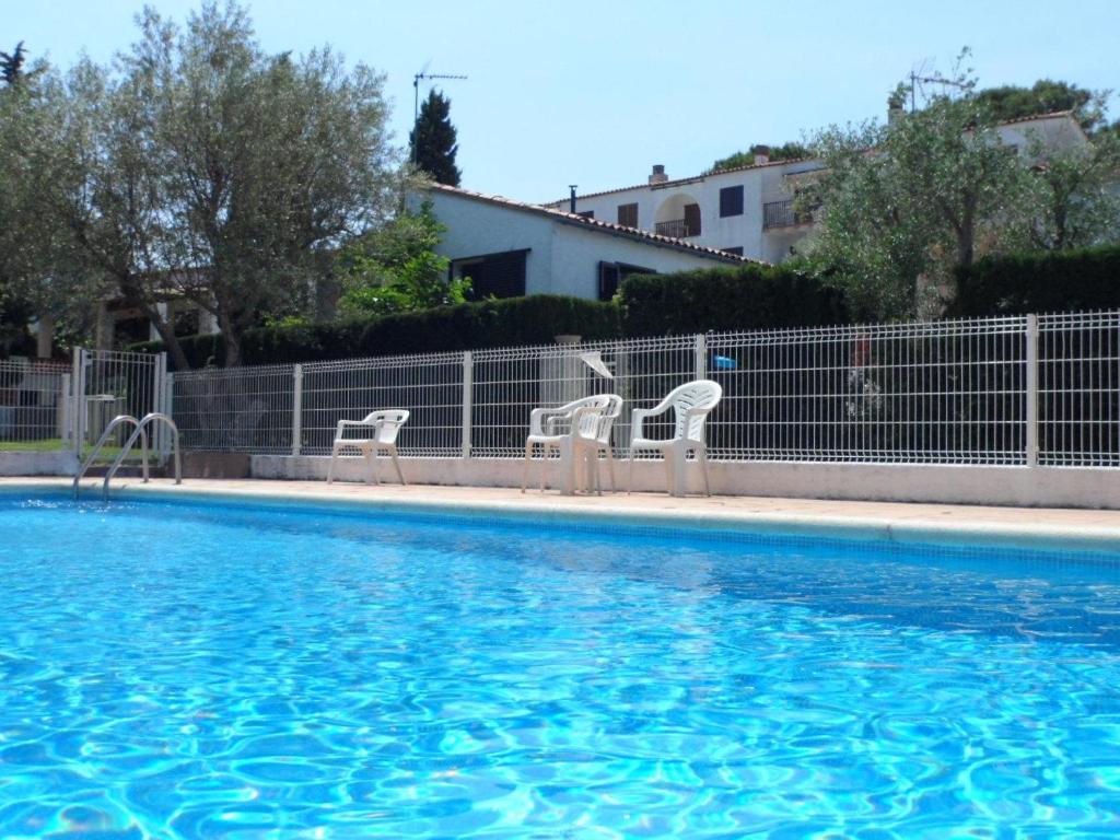 ein Pool mit drei Stühlen neben einem Zaun in der Unterkunft Apartamento L'Escala, 2 dormitorios, 4 personas - ES-325-37 in Torroella de Montgrí