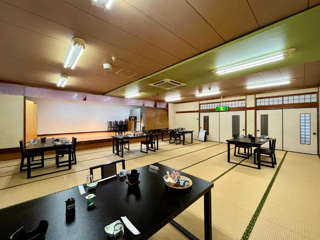 une grande chambre avec des tables et des chaises. dans l'établissement 旅館　松乃湯, à Kutami