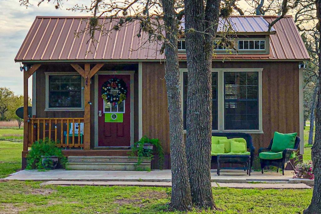 Casa pequeña con puerta morada y sillas verdes en Dancer - Reindeer Ranch at Round Top en Carmine