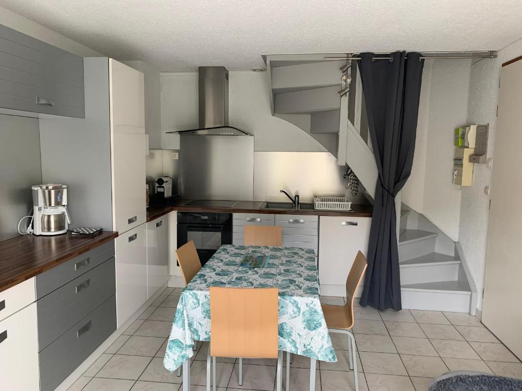 a kitchen with a table and chairs and a staircase at Maison à 50m de la Plage avec Parking Privatif - FR-1-482-140 in Fort-Mahon-Plage