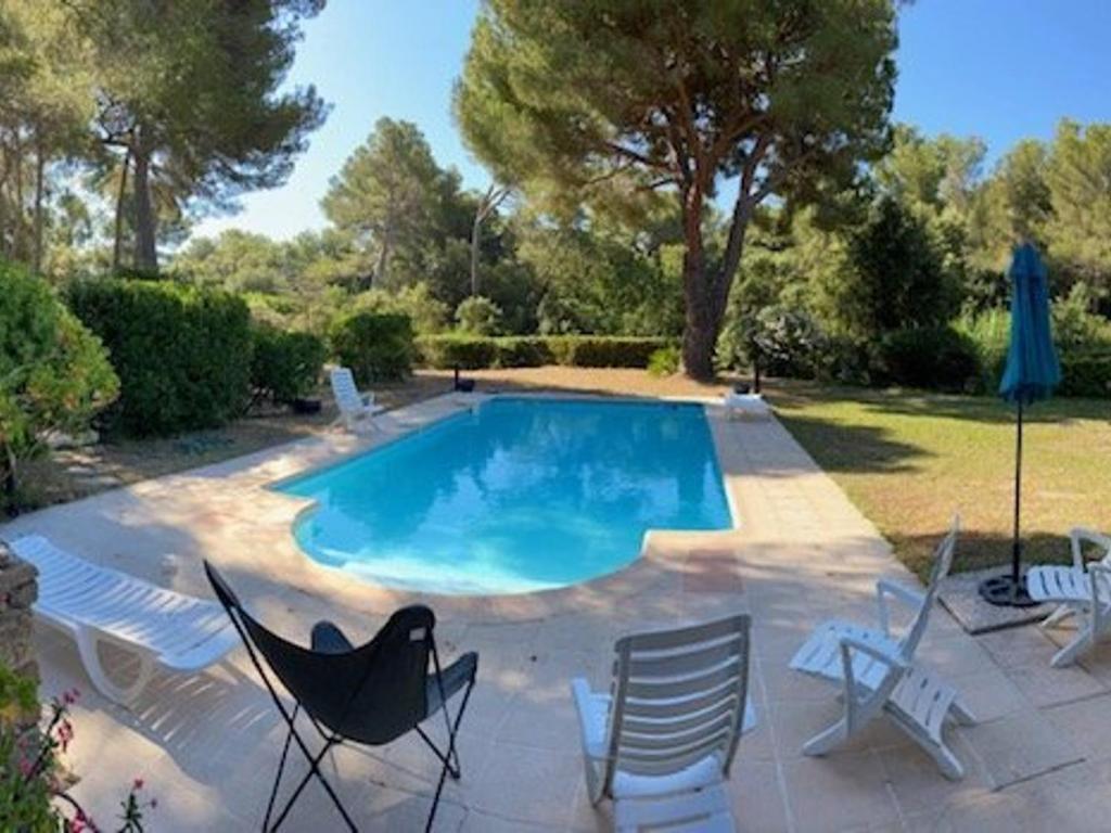 a swimming pool with chairs and a table and a umbrella at Maison Bormes-les-Mimosas, 4 pièces, 6 personnes - FR-1-251-721 in Bormes-les-Mimosas