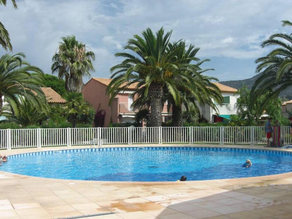 a swimming pool with a white fence and palm trees at Duplex 3 pièces climatisé avec piscine, terrasse et parking - Idéal famille au Lavandou - FR-1-251-732 in Le Lavandou