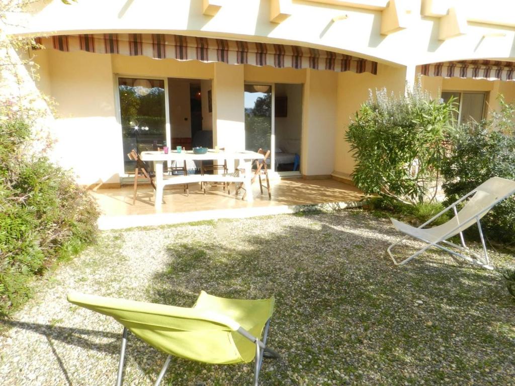 un patio avec une table et des chaises devant une maison dans l'établissement Charmant T2 avec grande terrasse à 250m de la plage - 4 couchages, garage privé, ménage inclus - FR-1-251-741, à Bormes-les-Mimosas