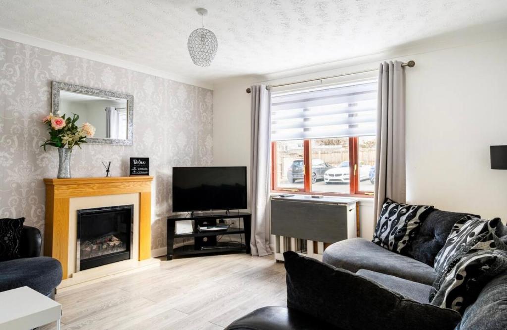 a living room with a fireplace and a television at Ochil View Holiday Let in Tullibody