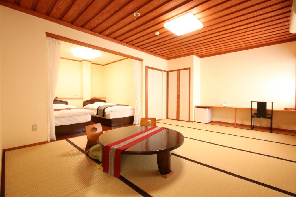 une chambre avec deux lits et une table dans une pièce dans l'établissement 旅館　松乃湯, à Kutami 11 autres photos