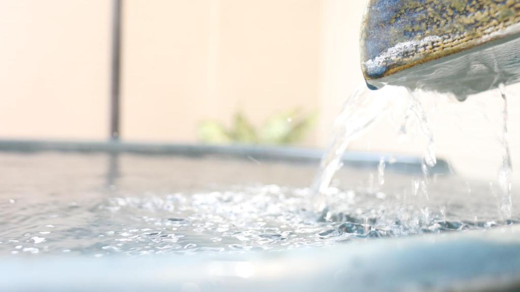un gros plan de l'eau qui coule d'une fontaine dans l'établissement 旅館　松乃湯, à Kutami