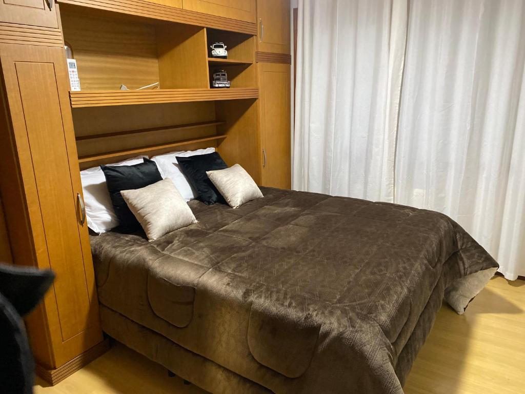 - une chambre avec un grand lit et des oreillers dans l'établissement LUXUOSO APT ALMERIS PECCIN no Centro de GRAMADO, à Gramado