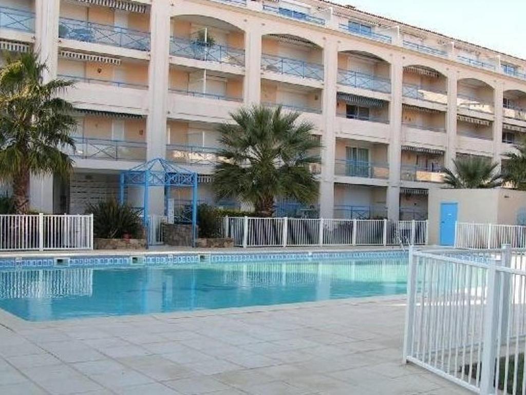 un hôtel avec une piscine devant un immeuble dans l'établissement Appartement T2 avec coin nuit, piscine, parking sécurisé, proche plage - Le Lavandou - FR-1-251-743, au Lavandou