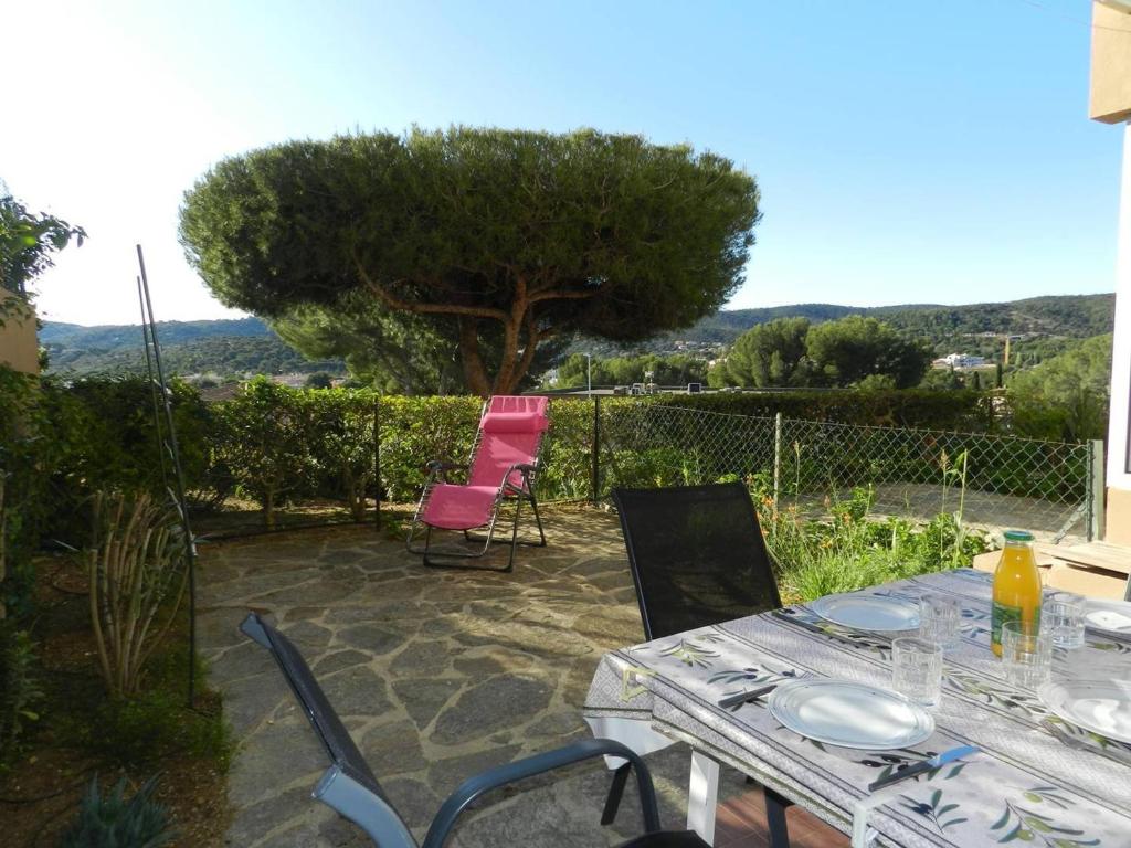 une table et des chaises sur une terrasse avec un arbre dans l'établissement Charmant T2 avec jardin, terrasse et parking à Bormes-les-Mimosas - FR-1-251-744, à Bormes-les-Mimosas