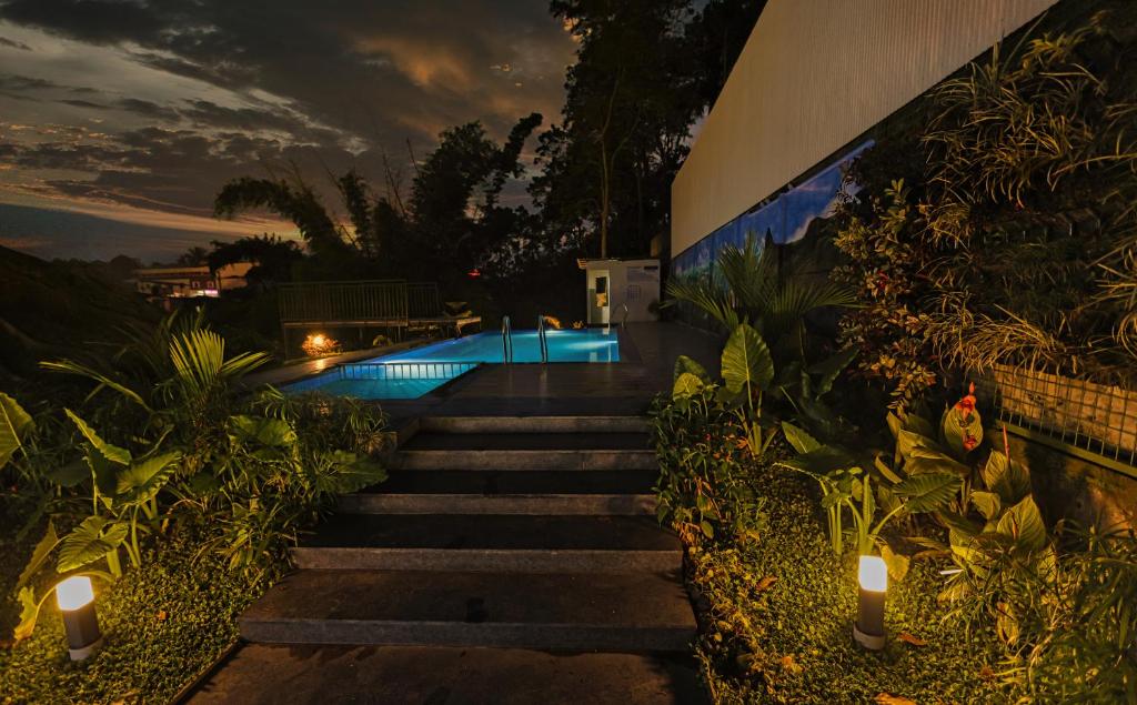 a set of stairs leading to a pool at night at Holidays Garden by Bestinn Leisure Wayanad in Kalpetta