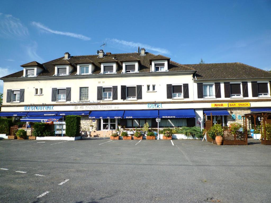 a large white building with a parking lot in front of it at Le Relais de la route bleue in Saint-Loup