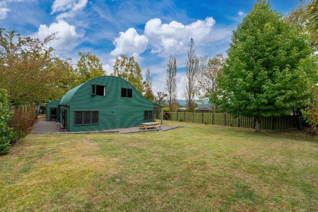 a green barn in a yard with a fence at Modern Barn Style - Taupo Holiday Home in Kinloch
