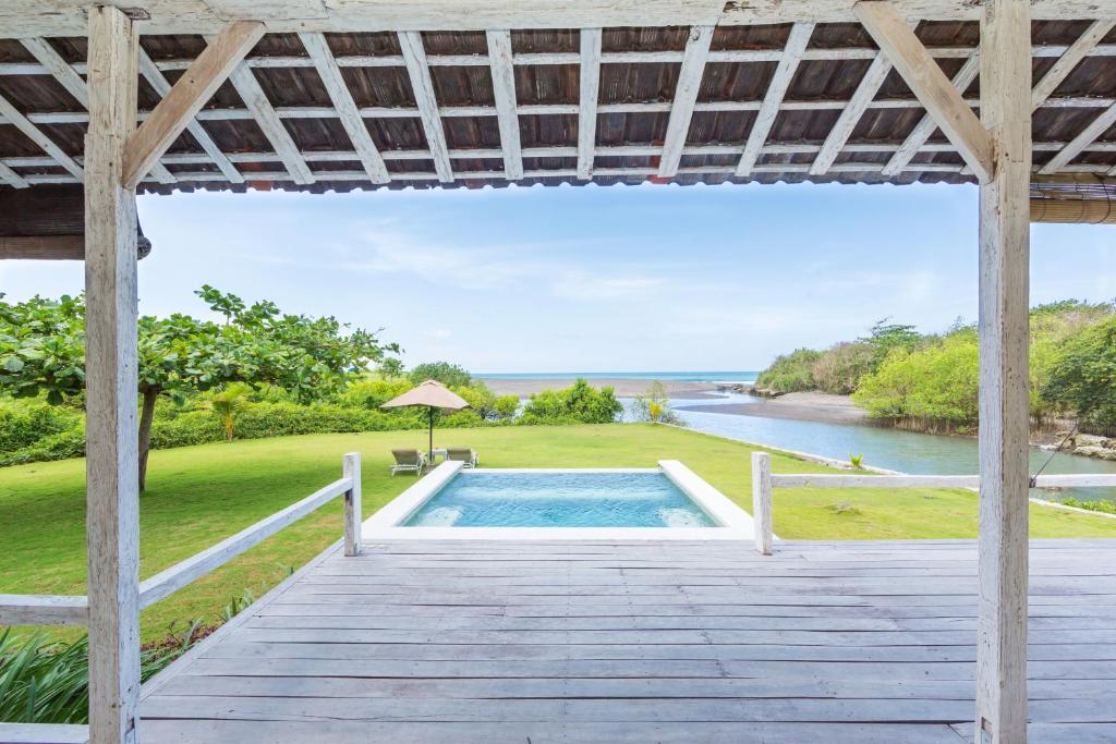 an outdoor deck with a pool and a view of the ocean at Villa Sungai Laut in Canggu