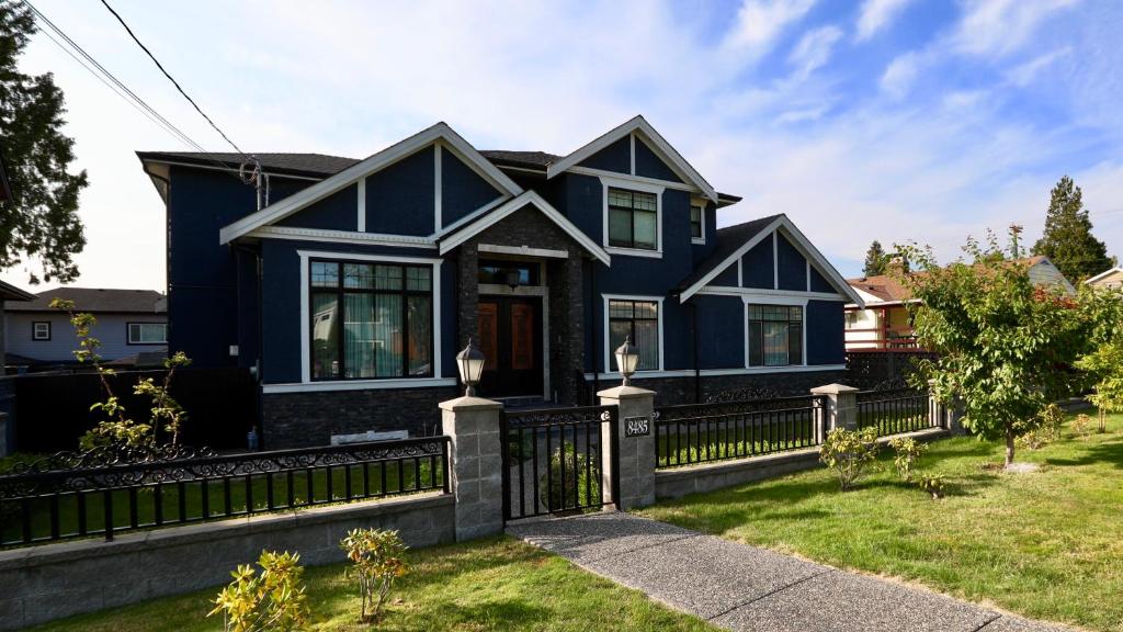 ein blaues Haus mit einem schwarzen Zaun in der Unterkunft Beautiful Home in Burnaby. (Lyn's Residence) in Burnaby