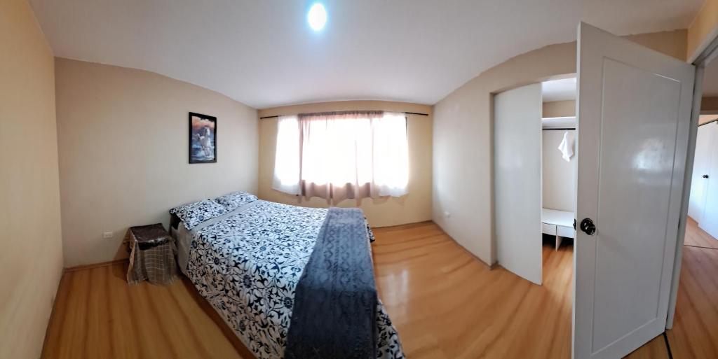 1 dormitorio con cama, ventana y puerta en Casa Anthony, en Cuenca