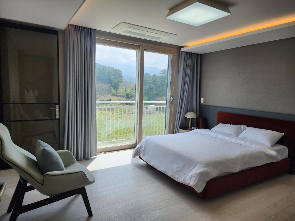 a bedroom with a bed and a chair and a window at Nobhillstay Jeju in Jeju