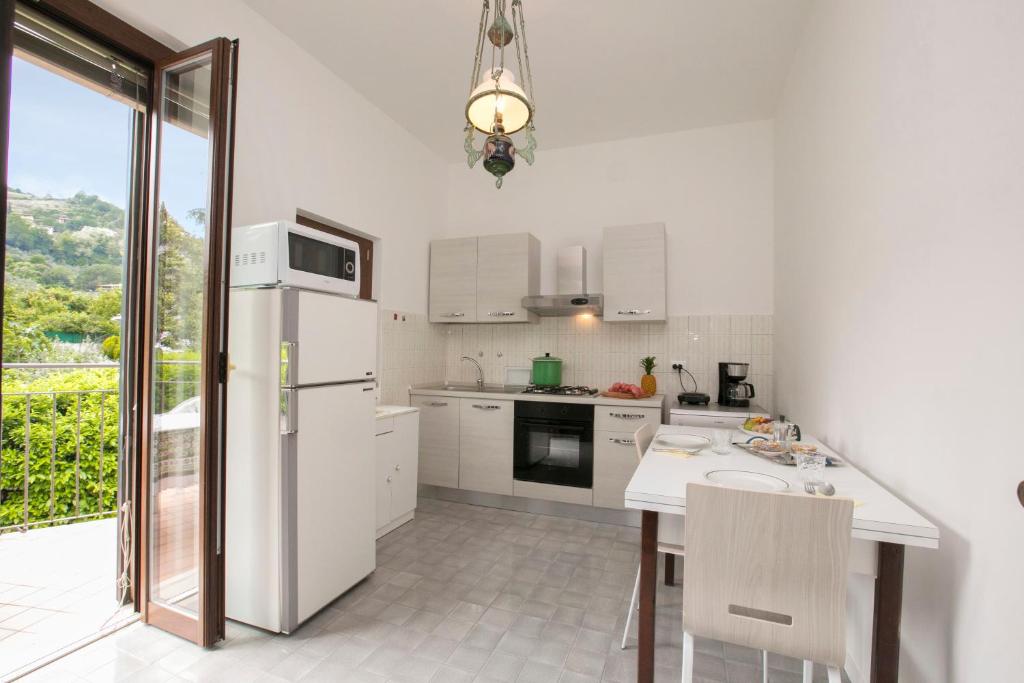 Biała kuchnia ze stołem i lodówką w obiekcie Villa Alberti Appartamento Emma - Happy Rentals w mieście Salò