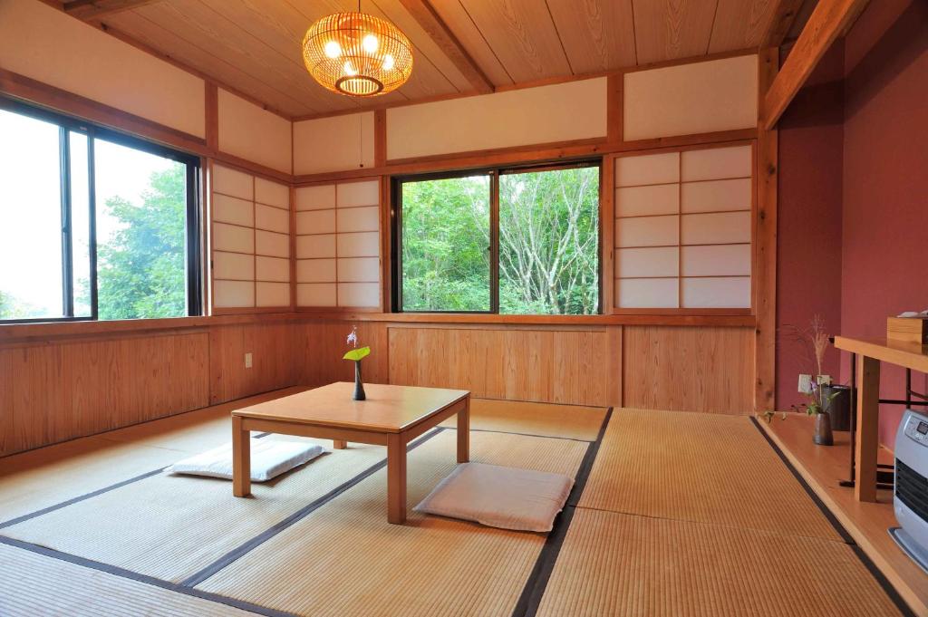 Cette chambre dispose d'une table et de fenêtres. dans l'établissement 山荘梶ヶ森, à Ōtakuchi